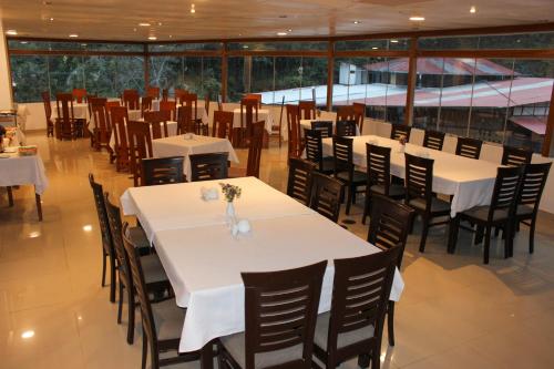 a restaurant with white tables and chairs and windows at Hotel Wiracocha Machupicchu in Machu Picchu