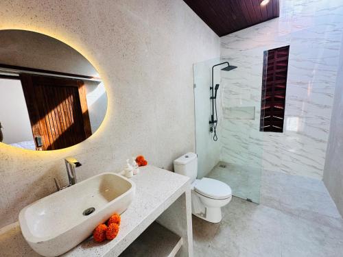 Un baño con lavabo, inodoro y espejo. en Kelapa Villa Mambal, en Mambat