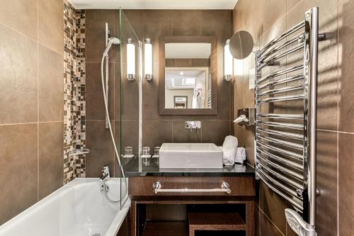 a bathroom with a tub and a sink and a mirror at Zenitude Hotel la Valadière, an Ascend Collection Hotel in Montpellier