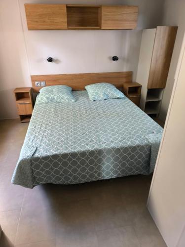 une chambre avec un lit avec une couette bleue dans l'établissement MH 201 AGREABLE et tout ÉQUIPÉ 2CH dont suite parentale et 2sdb avec vue sur foret dans camping 4 étoiles, à Saint-Julien-en-Born