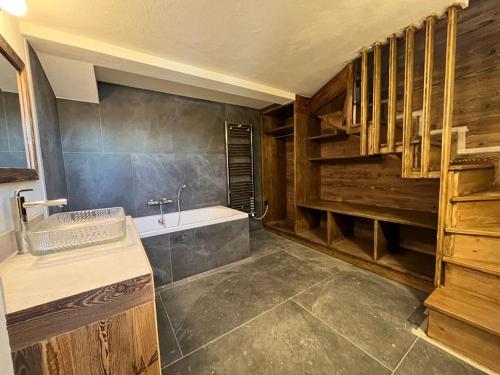 La salle de bains est pourvue de murs en bois, d'une baignoire et d'un lavabo. dans l'établissement La Belle Etoile, à Saint-Gervais-les-Bains