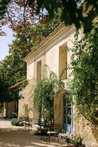 un bâtiment avec des tables et des chaises devant lui dans l'établissement 84B4 - Glycine suite in an 18th century Provencal farmhouse, à Althen-des-Paluds
