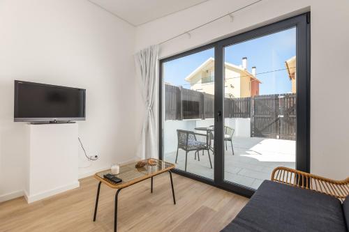 a living room with a couch and a tv at Casa Camarinhas in São Jacinto