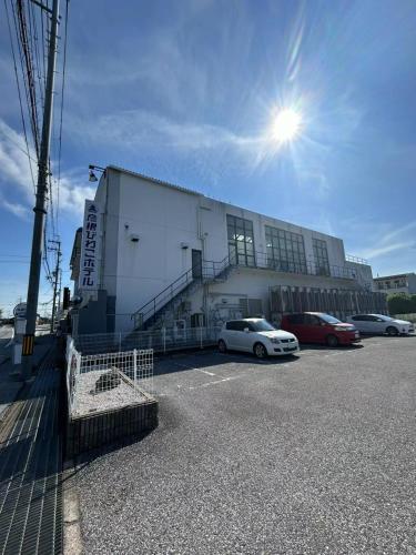a building with two cars parked in a parking lot at 彦根びわこホテル裏のマンション 一室貸し切り50台無料駐車場付き台所あり自転車貸出可 BbQ可 ペット同伴可 in Hikone