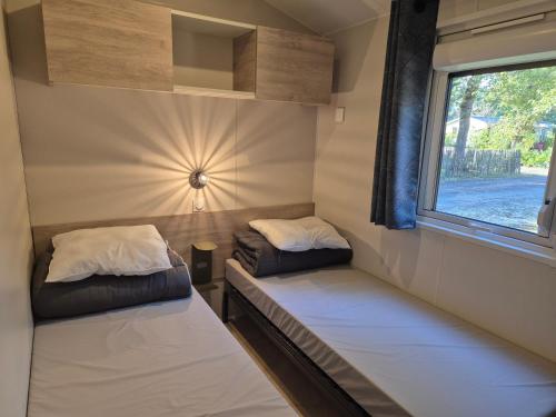 zwei Betten in einem kleinen Zimmer mit Fenster in der Unterkunft Cottage Les 2 Chardon in La Teste-de-Buch