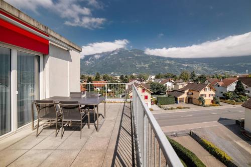 a balcony with a table and chairs and a view of a city at Wohntel - wohnen wie im Hotel in Sevelen