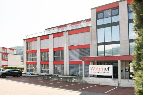 a building with a sign in a parking lot at Wohntel - wohnen wie im Hotel in Sevelen