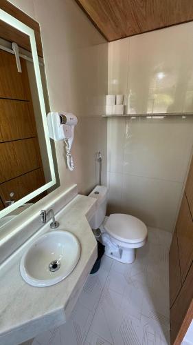 a bathroom with a white toilet and a sink at Alfa Mar Pousada in Abraão