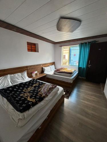 a bedroom with two beds and a window at Odyssey Stays Joshimath - Near Narsingh Temple in Joshīmath