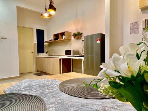 a kitchen with a refrigerator and a table with flowers at The Atlantis Residence, 1-5pax in Tranquerah