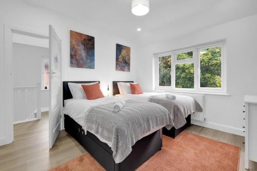 a bedroom with two beds and two windows at Inspira Stays - Spacious Modern House in Leicester - Free Parking - Xbox, Table Football & Smart TV in Braunstone