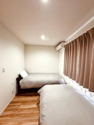 two beds in a small room with wooden floors at Niseko Purr 203 in Ōmagari