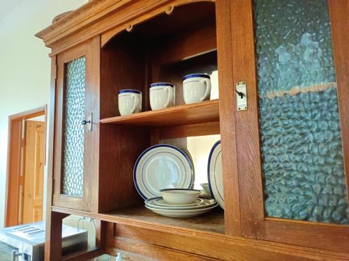 a wooden cabinet with plates and dishes in it at Penzion SPORTINO in Svoboda nad Úpou