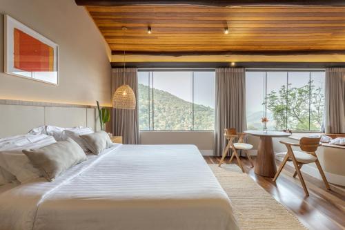 a bedroom with a large white bed and a desk at Pousada A Rosa e o Rei in São Francisco Xavier