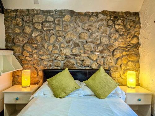 a bedroom with a stone wall with a bed with two lamps at Clyne Farm Centre in The Mumbles