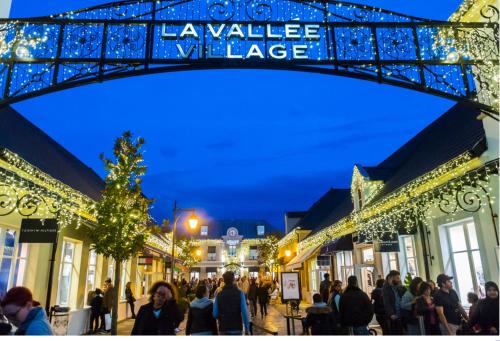 a group of people walking down a street with christmas lights at Immodēly & la Magie de Disney in Serris