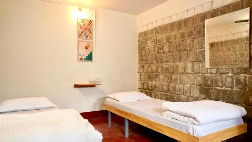 two beds in a room with a brick wall at Roambay - Gokulam in Mysore