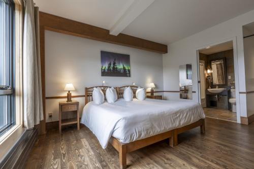 a bedroom with a large white bed and a bathroom at Auberge de Montagne des Chic-Chocs Mountain Lodge - Sepaq in Sainte-Anne-des-Monts