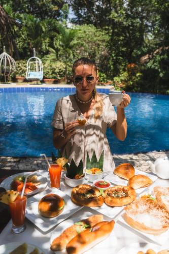 a woman sitting at a table with a plate of food at Sundaras Infinity Jungle Resort in Dambulla