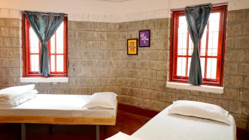 two beds in a room with two windows at Roambay - Gokulam in Mysore