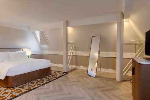 a hotel room with a bed and a mirror at InterContinental Hotels Chantilly Chateau Mont Royal by IHG in Chantilly