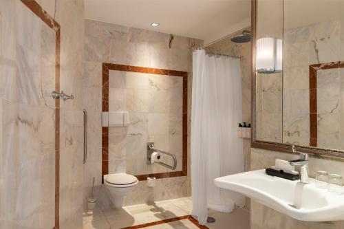 a bathroom with a toilet and a sink and a shower at InterContinental Hotels Chantilly Chateau Mont Royal by IHG in Chantilly