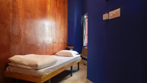 a bed in a room with a blue wall at Roambay - Gokulam in Mysore