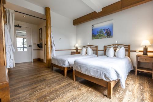 two beds in a room with wooden floors at Auberge de Montagne des Chic-Chocs Mountain Lodge - Sepaq in Sainte-Anne-des-Monts