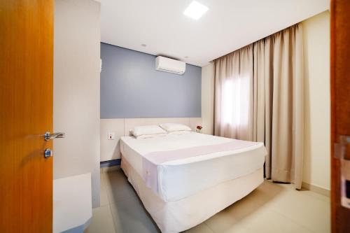 a bedroom with a large white bed and a window at Vinhedo Plaza Hotel in Vinhedo