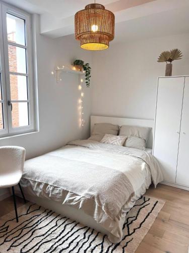 a white bedroom with a bed and a chandelier at Le Saphir in Toulouse