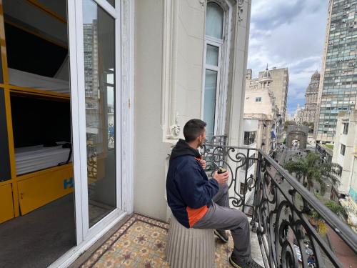 a man sitting on a ledge on a balcony at Viajero Montevideo Hostel in Montevideo