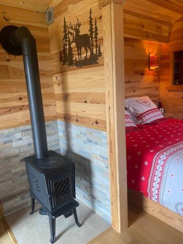 a log cabin with a stove in a bedroom at Au Paradou du Bûcheron Adults only in Lessive