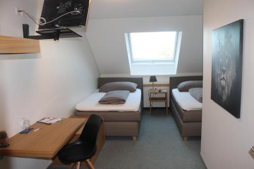 a small room with two beds and a desk and a window at Landgasthof Lowen in Sulgen