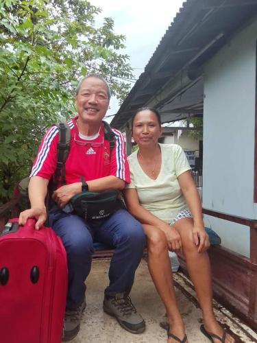 a man and a woman sitting on a bench with a suitcase at Naca Homestay in Manado