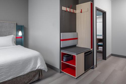 a small bedroom with a bed and a mirror at avid hotel North Platte by IHG in North Platte