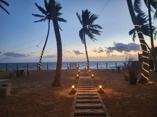 a pathway on the beach with candles and palm trees at Adique's Resorts in Marawila