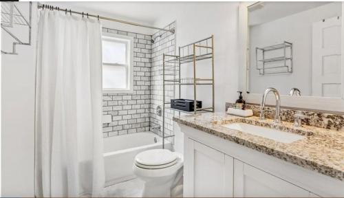 a white bathroom with a toilet and a sink at Historic New Orleans in the Treme in New Orleans
