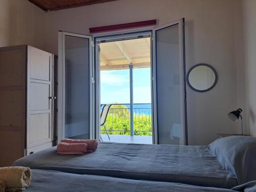 a bedroom with a bed with a view of the ocean at BIZOS Beach in Koroni