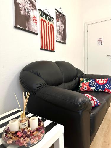 a black leather couch in a living room with a table at Leaning Tower Rooms Free Parking Self Check In in Pisa
