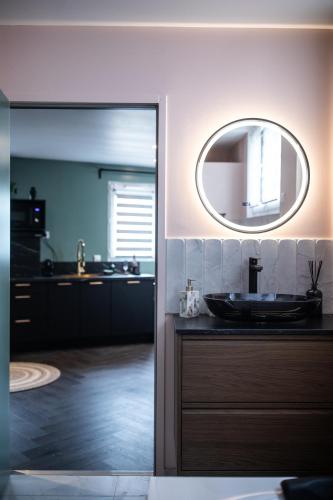 une salle de bain avec un lavabo et un miroir dans l'établissement Reflet des sens Love & Balnéo, à Sainte-Adresse