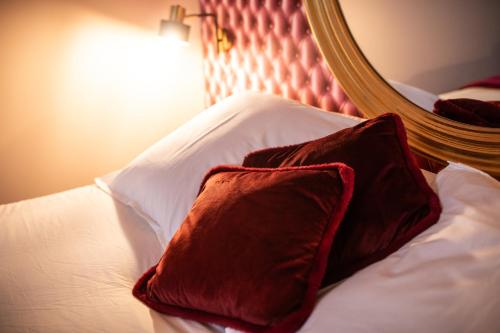- un oreiller rouge sur un lit avec un miroir dans l'établissement Reflet des sens Love & Balnéo, à Sainte-Adresse