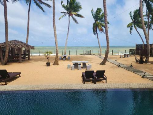 a view of a beach with palm trees and a pool at Adique's Resorts in Marawila