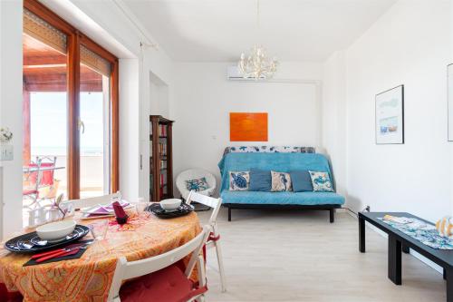 a living room with a table and a blue couch at Ostia Attico fronte mare in Lido di Ostia