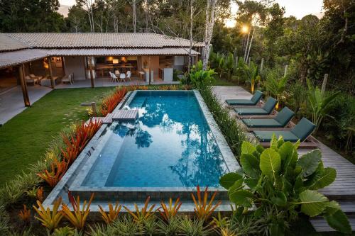 an image of a swimming pool with chairs and a house at Villa da Lua - Aconchego e sofisticação em meio à natureza in Arraial d'Ajuda
