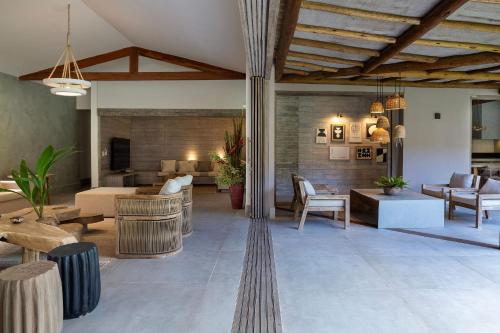 a living room with a couch and tables and chairs at Villa da Lua - Aconchego e sofisticação em meio à natureza in Arraial d'Ajuda