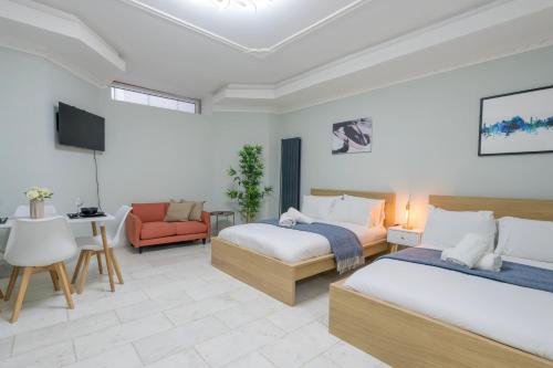 a hotel room with two beds and a chair at Finchley Road Studios & Apartments by PrimeCityHosts in London