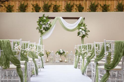 an aisle with white chairs and a marquee with flowers at Falls Church Marriott Fairview Park in Falls Church