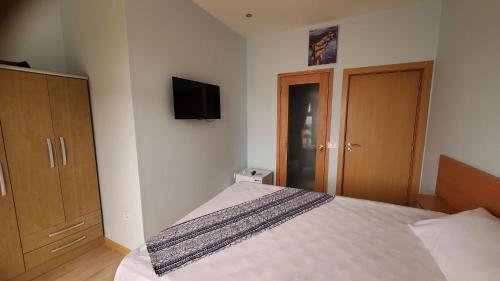 a bedroom with a bed and a tv on the wall at Fajã Beach House 2 in Fajã