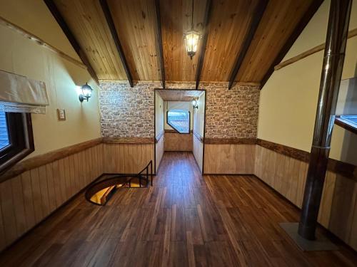 an empty room with wood floors and a hallway at Cabañas y Casa Kauken in Puerto Natales