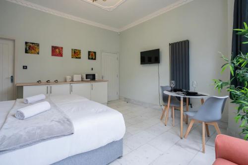 a bedroom with a bed and a table and a chair at Finchley Road Studios & Apartments by PrimeCityHosts in London